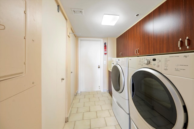 clothes washing area with cabinets and washer and clothes dryer