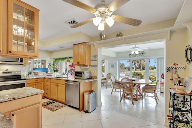 kitchen featuring light stone countertops, appliances with stainless steel finishes, light brown cabinets, sink, and light tile patterned flooring