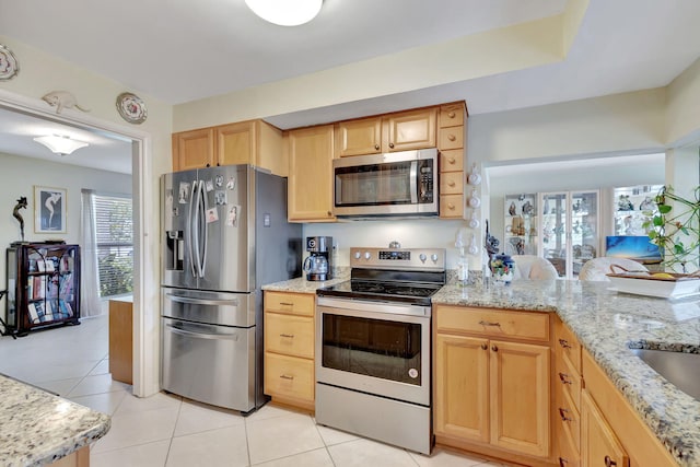 kitchen with light tile patterned flooring, appliances with stainless steel finishes, light brown cabinets, and light stone counters