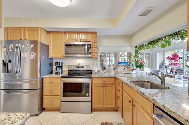 kitchen featuring light tile patterned floors, stainless steel appliances, light brown cabinetry, and sink