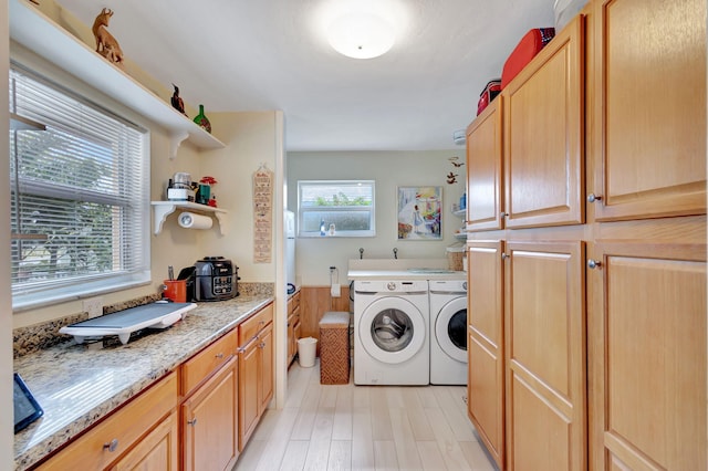 laundry area with light hardwood / wood-style floors, plenty of natural light, and washer and clothes dryer