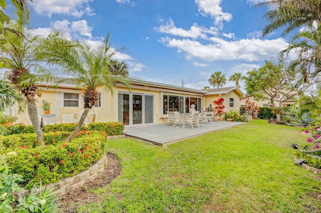 back of property with a deck and a lawn