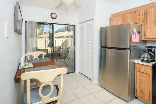 kitchen featuring stainless steel fridge, light tile patterned floors, and ceiling fan