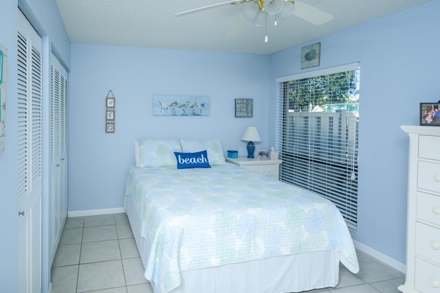 bedroom featuring ceiling fan, light tile patterned flooring, and a textured ceiling