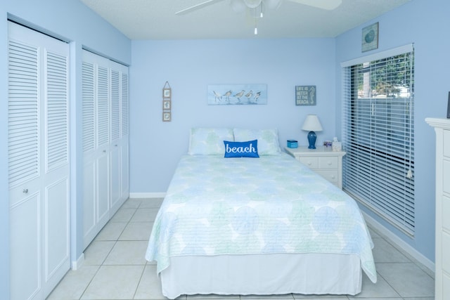 tiled bedroom with multiple closets, ceiling fan, and a textured ceiling