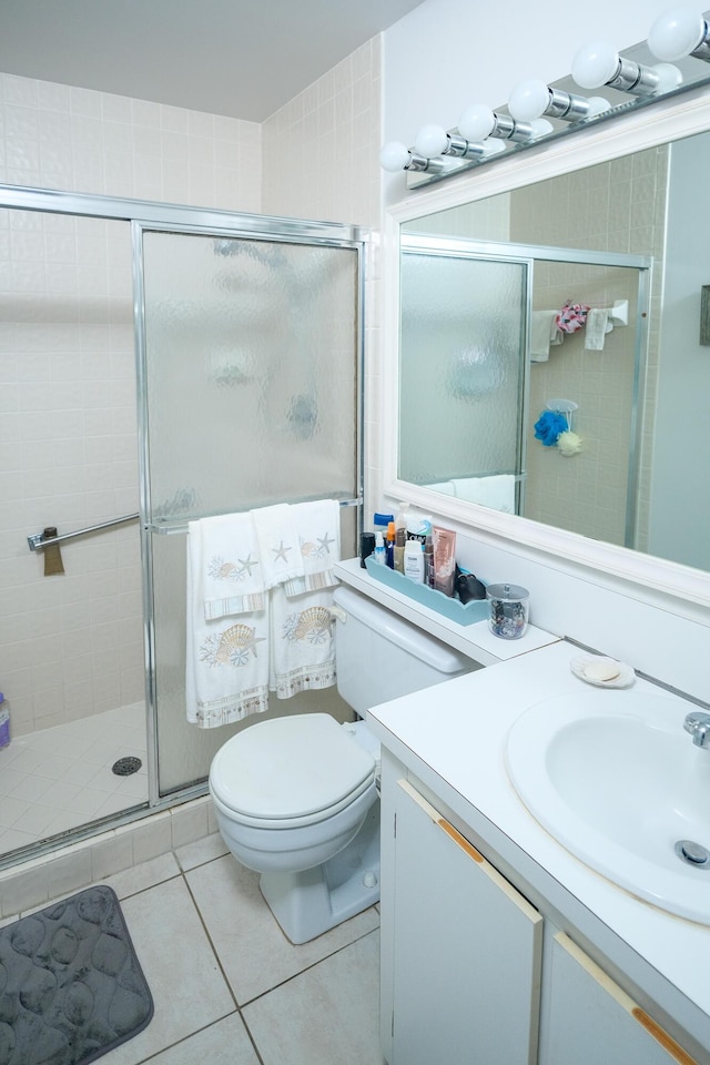 bathroom with tile patterned floors, vanity, toilet, and a shower with door