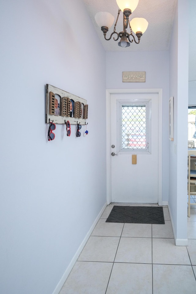 doorway to outside featuring light tile patterned floors, a textured ceiling, and an inviting chandelier