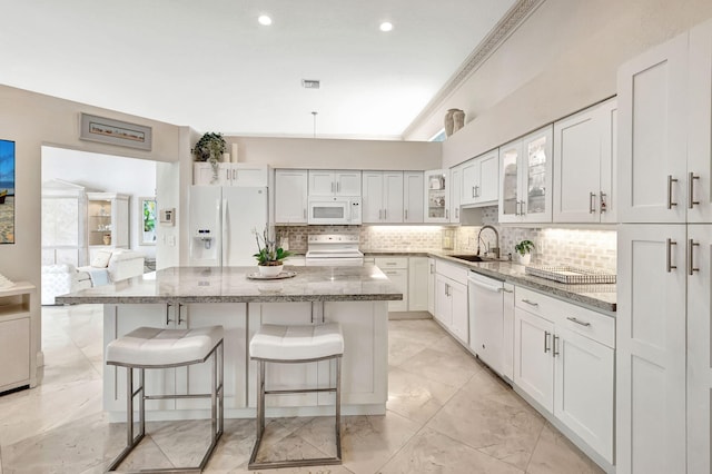 kitchen with sink, white cabinetry, white appliances, a kitchen breakfast bar, and light stone countertops