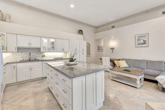 kitchen featuring a kitchen island, white cabinetry, light stone counters, and sink