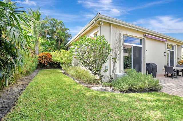 view of property exterior featuring a patio and a lawn