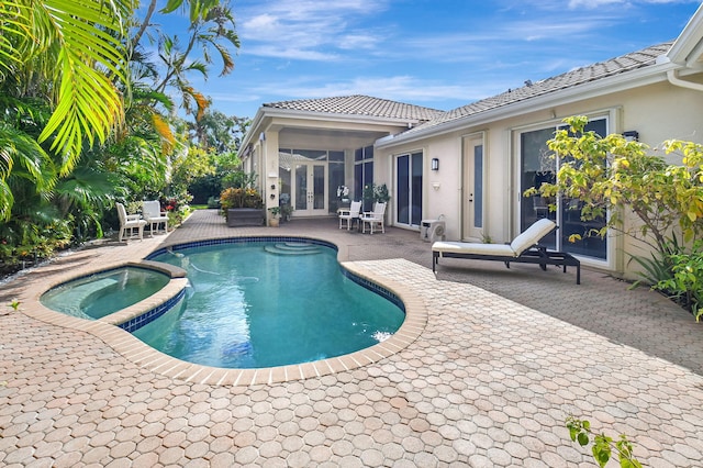 view of pool with french doors, an in ground hot tub, and a patio