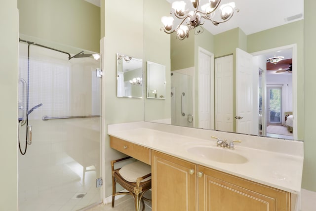 bathroom featuring a shower with door, vanity, and ceiling fan with notable chandelier