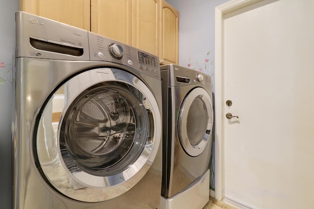 washroom with cabinets and washing machine and clothes dryer