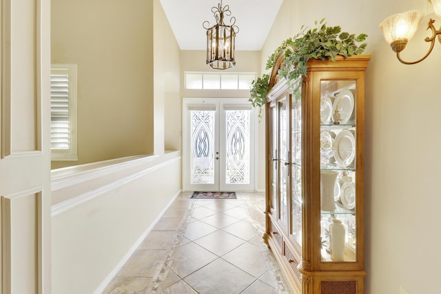 foyer with french doors, light tile patterned floors, vaulted ceiling, and an inviting chandelier