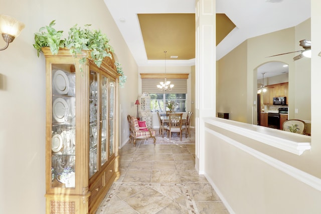 corridor featuring a raised ceiling and a notable chandelier