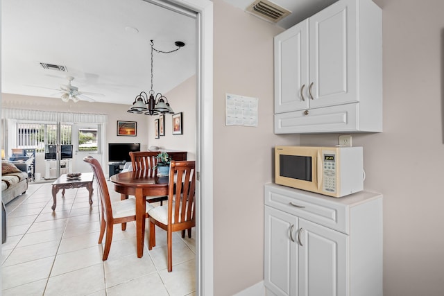 dining space featuring light tile patterned floors and ceiling fan with notable chandelier