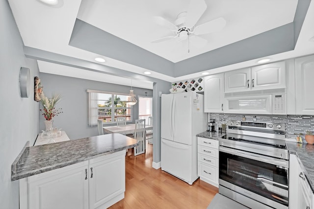 kitchen featuring light wood-type flooring, white appliances, a tray ceiling, decorative light fixtures, and white cabinetry