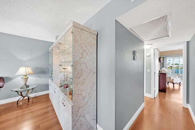 hallway featuring light wood-type flooring and a textured ceiling