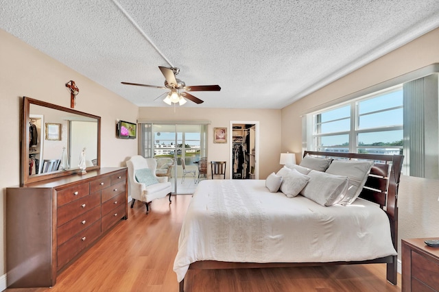 bedroom featuring a walk in closet, ceiling fan, a closet, and multiple windows