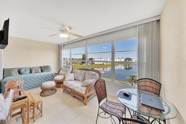 sunroom with ceiling fan and a water view