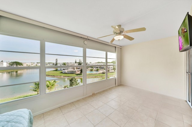 sunroom featuring ceiling fan and a water view