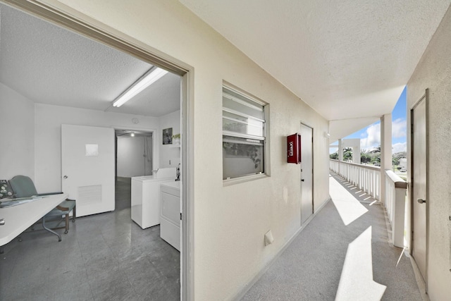 hallway featuring a textured ceiling and washing machine and clothes dryer