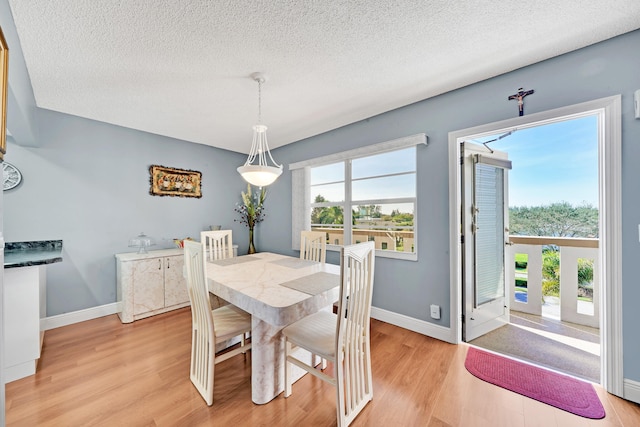 dining area with a textured ceiling and light wood-type flooring