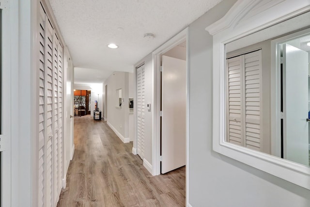 corridor featuring light wood-type flooring and a textured ceiling