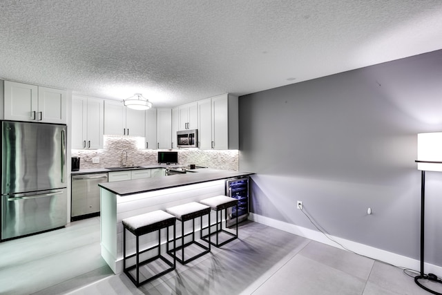 kitchen featuring a kitchen bar, white cabinetry, stainless steel appliances, sink, and kitchen peninsula