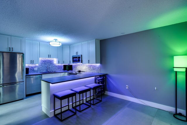 kitchen featuring white cabinets, kitchen peninsula, appliances with stainless steel finishes, and a breakfast bar area