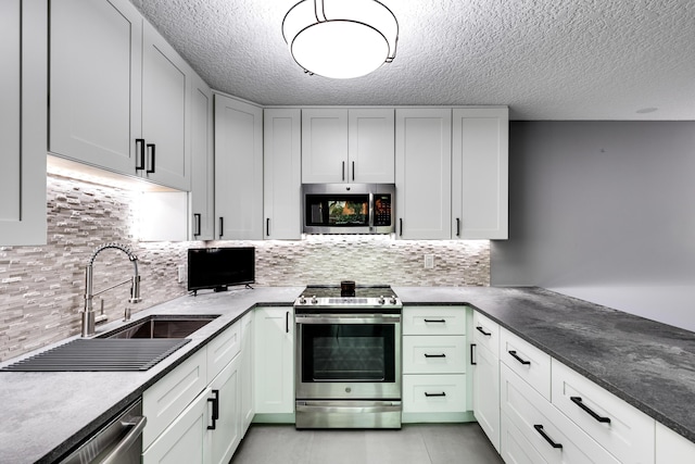 kitchen with decorative backsplash, appliances with stainless steel finishes, sink, and white cabinetry