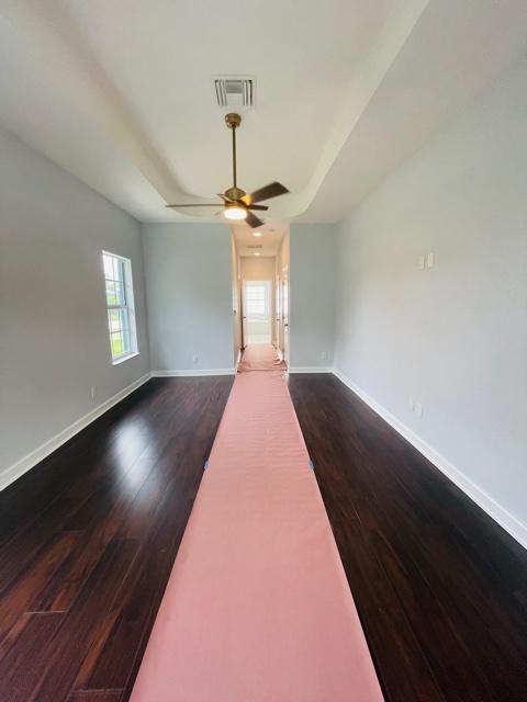 unfurnished living room featuring ceiling fan and dark wood-type flooring