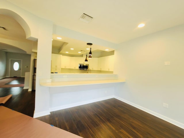 kitchen with sink, dark hardwood / wood-style flooring, kitchen peninsula, pendant lighting, and white cabinets