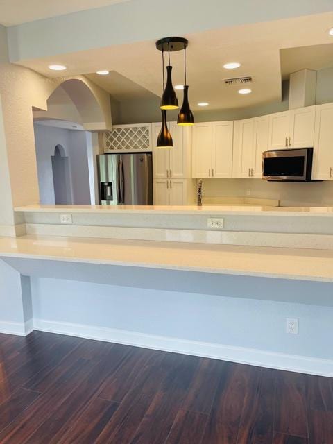 kitchen featuring white cabinets, dark hardwood / wood-style floors, stainless steel appliances, and hanging light fixtures