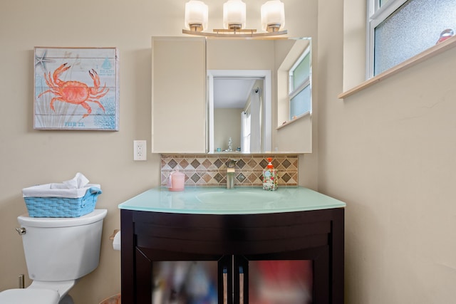 bathroom with toilet, vanity, and decorative backsplash