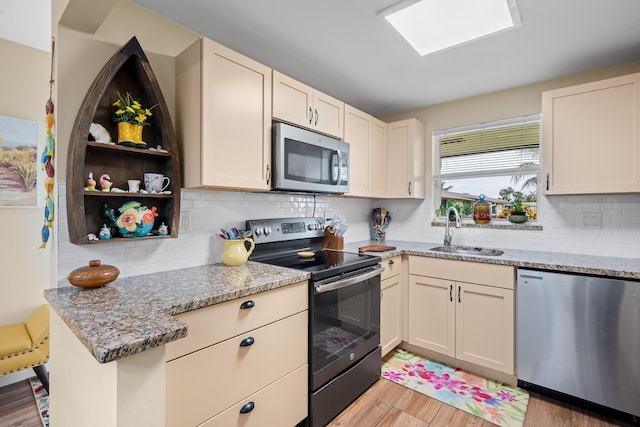 kitchen featuring appliances with stainless steel finishes, light wood-type flooring, light stone countertops, and sink