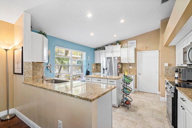 kitchen with stainless steel appliances, vaulted ceiling, white cabinetry, and light stone counters