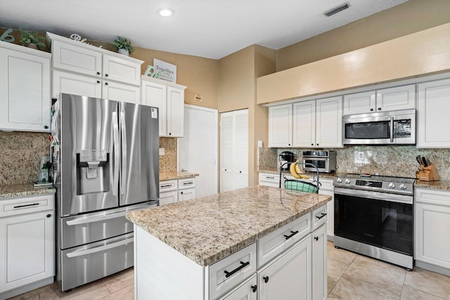 kitchen with white cabinetry, a kitchen island, light tile patterned floors, and appliances with stainless steel finishes