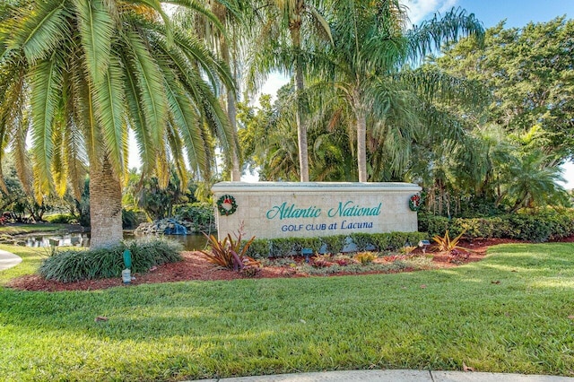 community sign featuring a lawn and a water view