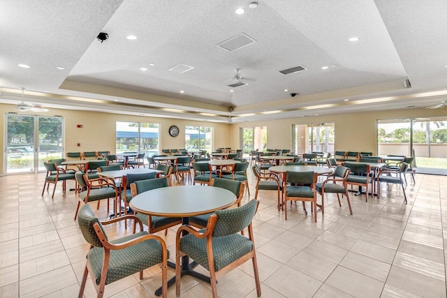 dining area with a textured ceiling, a tray ceiling, ceiling fan, and light tile patterned flooring