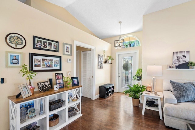 foyer entrance featuring a textured ceiling, a chandelier, dark wood-type flooring, and vaulted ceiling