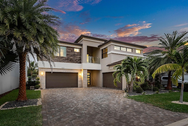 view of front of house featuring a yard, a balcony, and a garage