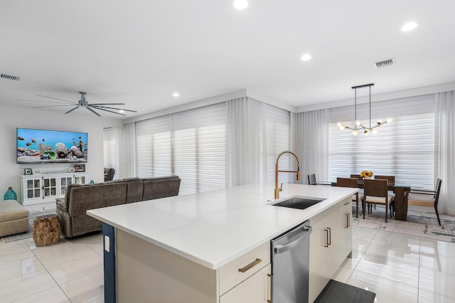 kitchen featuring a center island with sink, sink, stainless steel dishwasher, light tile patterned floors, and decorative light fixtures