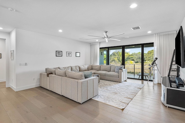 living room with light hardwood / wood-style flooring and ceiling fan