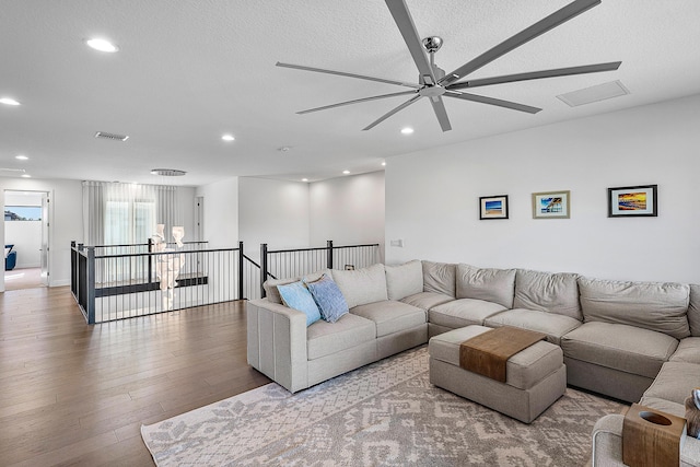 living room with a textured ceiling, light hardwood / wood-style floors, and ceiling fan