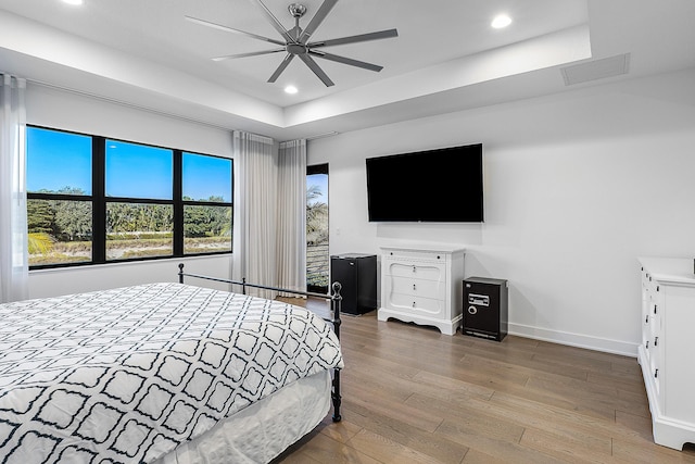 bedroom featuring a raised ceiling, ceiling fan, and hardwood / wood-style flooring