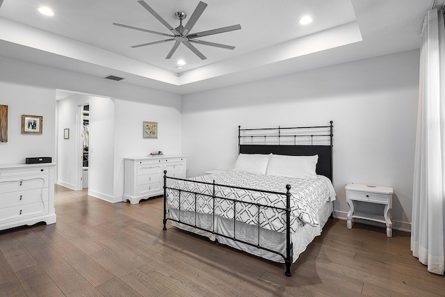 bedroom with a tray ceiling, ceiling fan, and dark hardwood / wood-style flooring