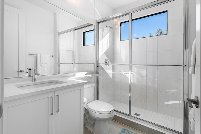 bathroom featuring tile patterned flooring, vanity, toilet, and a shower with shower door