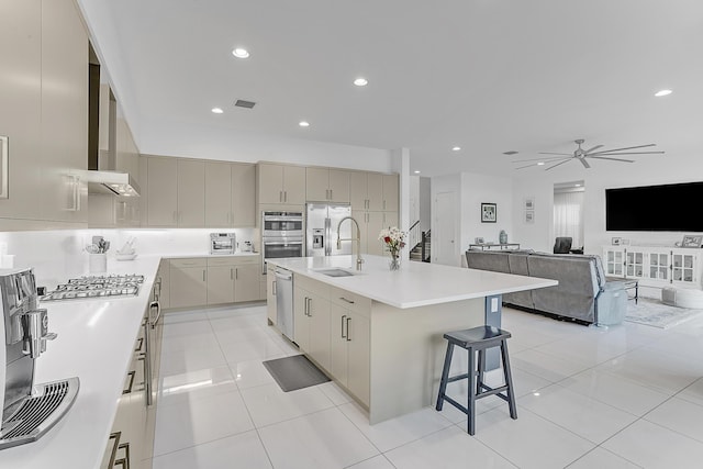 kitchen with a spacious island, sink, ceiling fan, light tile patterned floors, and stainless steel appliances