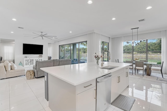 kitchen with a kitchen island with sink, sink, hanging light fixtures, stainless steel dishwasher, and white cabinetry